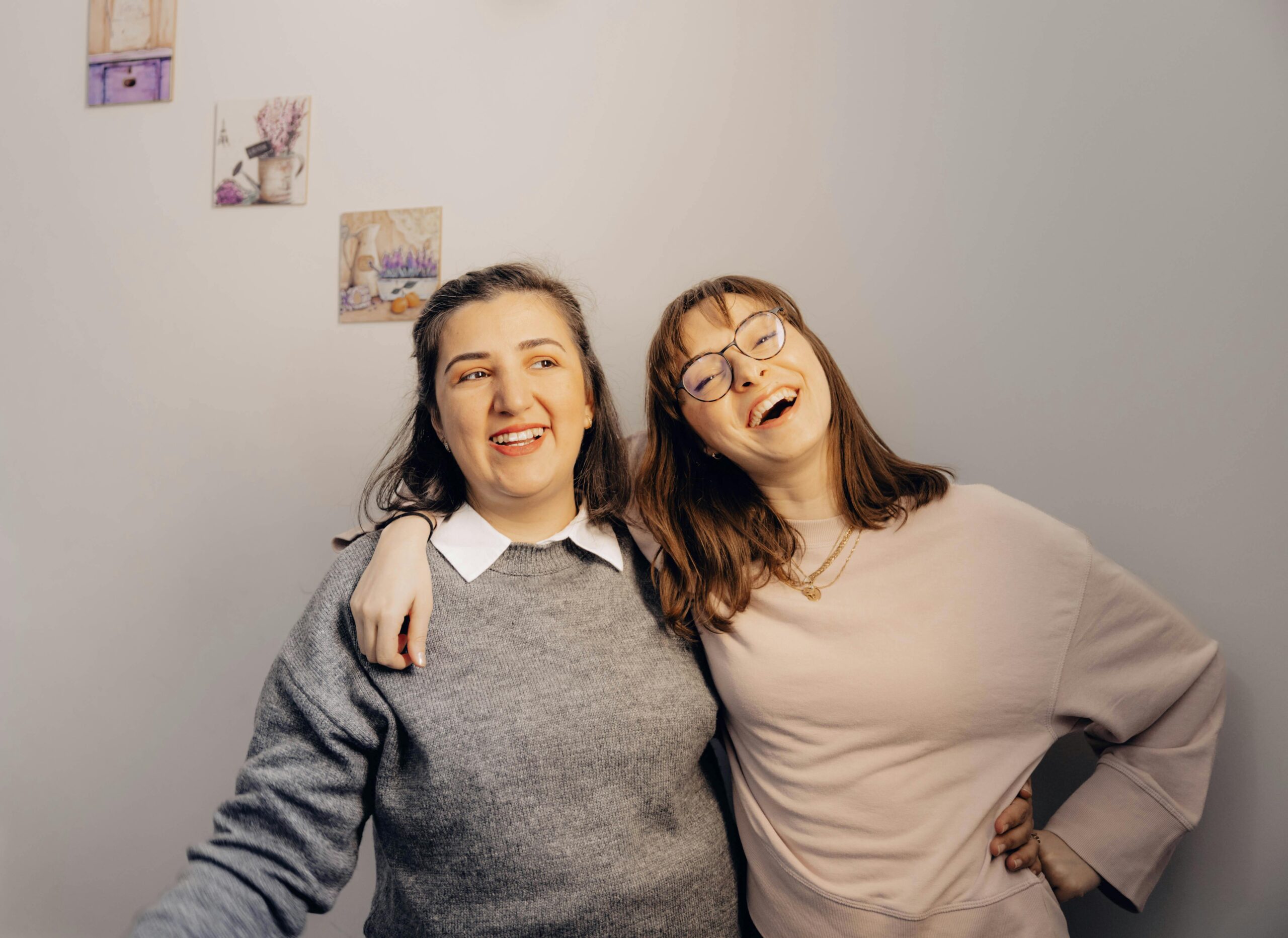 Warm and joyful moment of two friends laughing and embracing indoors.
